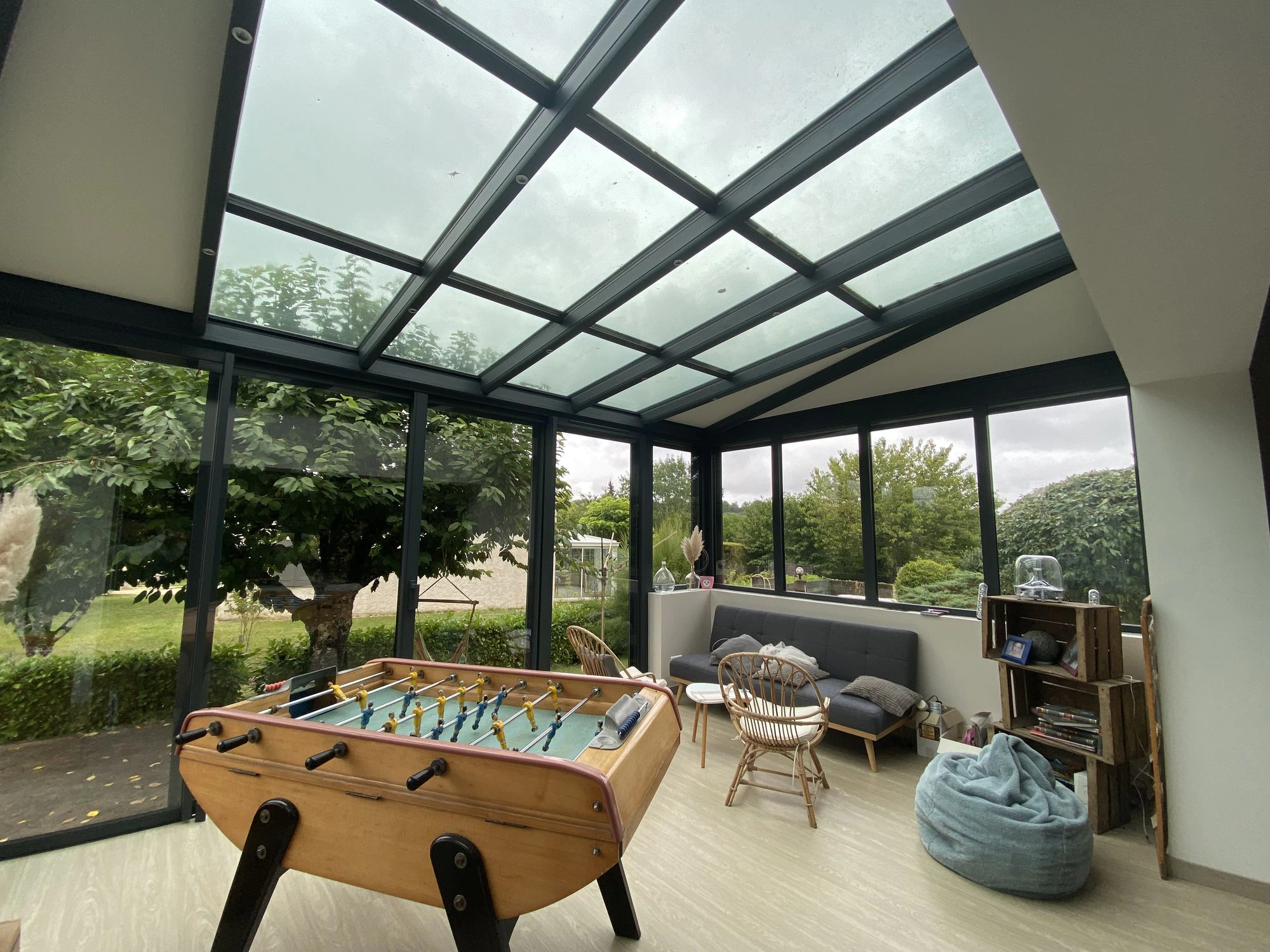 une table de billard à l'intérieur d'une pièce avec un toit en verre