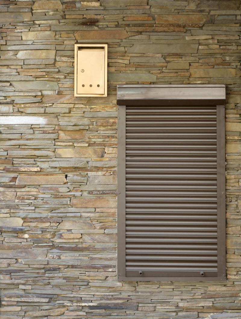 une fenêtre aux volets bruns à côté d'un mur de briques
